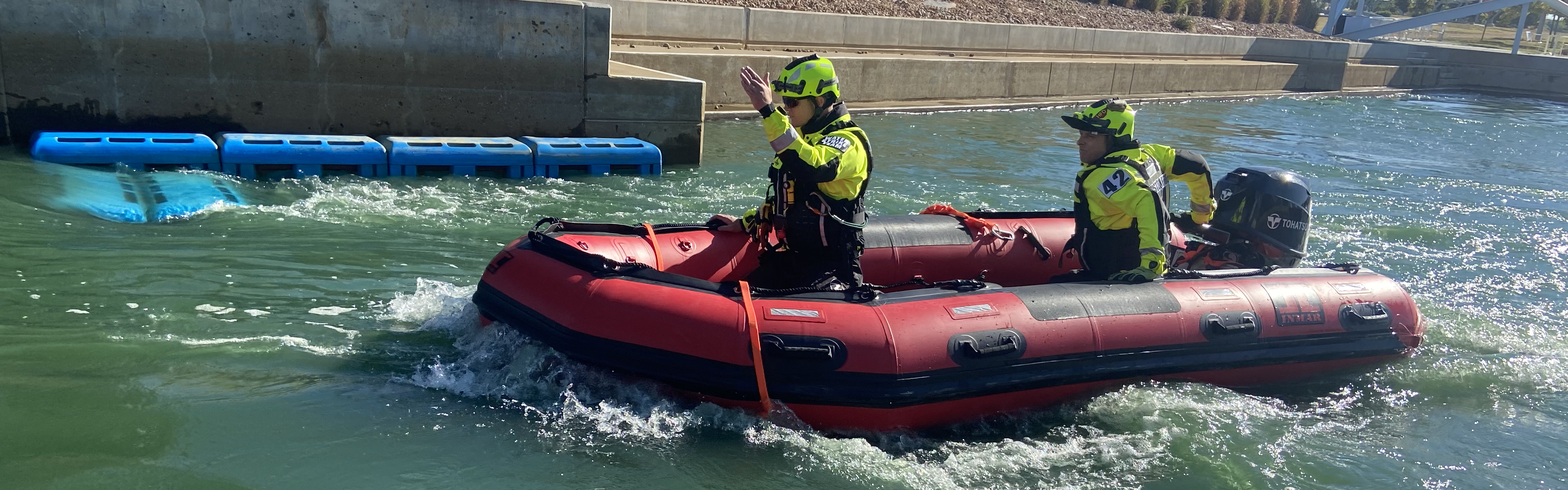 two houston firefighters in a rescue boat in the water.